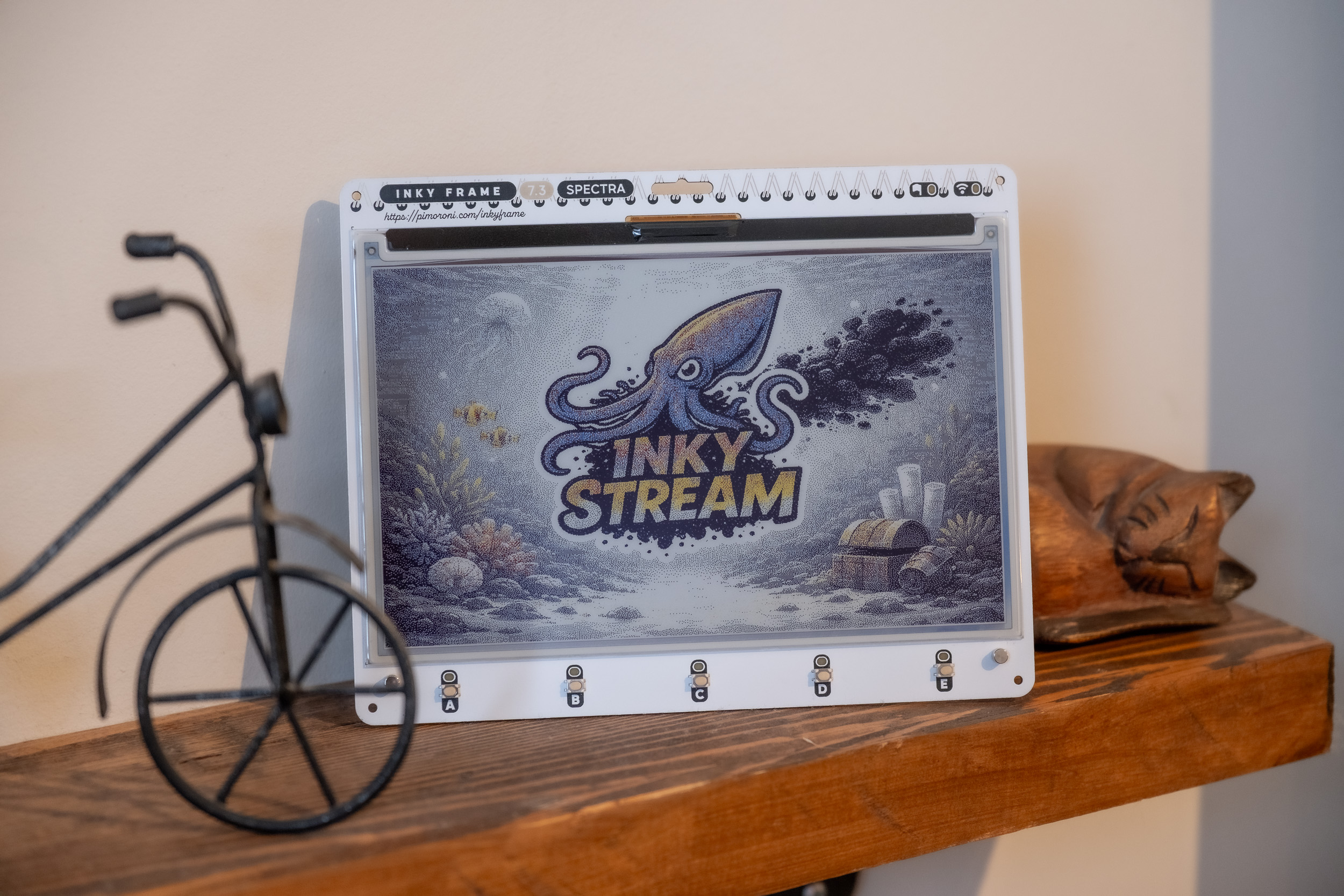 Inky Frame on a shelf displaying a colour photograph, with the InkyStream logo